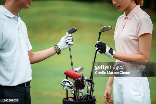 crop shot of asian chinese young couple golfer taking out driver club from golf bag on the golf course - golf accessories stock pictures, royalty-free photos & images