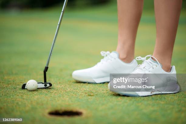 sluit omhoog van aziatische chinese jonge vrouwelijke golfer die in de bal aan een golfgat op de golfcursus tikt - women's golf stockfoto's en -beelden