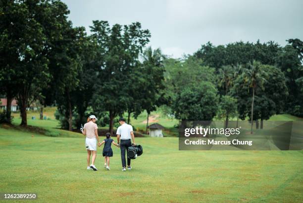 rear view of asian chinese smiling young family golfer having fun and bonding with daughter on the golf course - golf day stock pictures, royalty-free photos & images