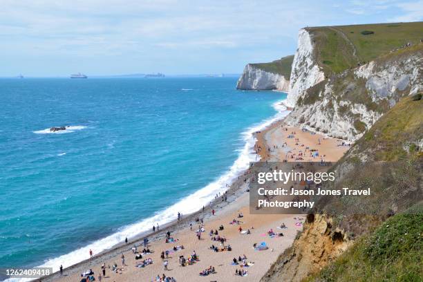 the beach at durdle door full of people relaxing - dorset england stock pictures, royalty-free photos & images