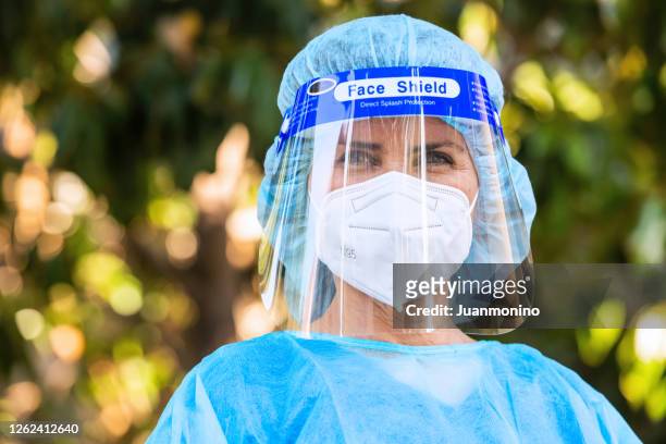 müde, überlastete, erschöpfte medizinische helfer posiert außerhalb des krankenhauses während einer pause - face shield stock-fotos und bilder