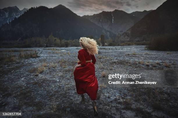 woman in a red victorian dress running away through the rocky area. nicely fits for book cover - red dress run stock pictures, royalty-free photos & images