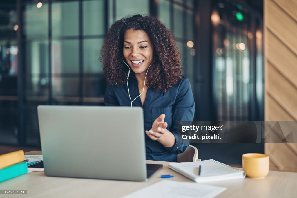 Femme d’affaires de sourire pendant un appel vidéo dans le bureau