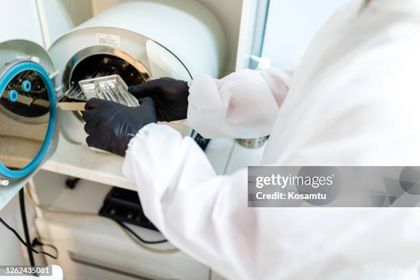 dentist assistant taking sterile dentist tray with instruments from autoclave - mikado stock pictures, royalty-free photos & images