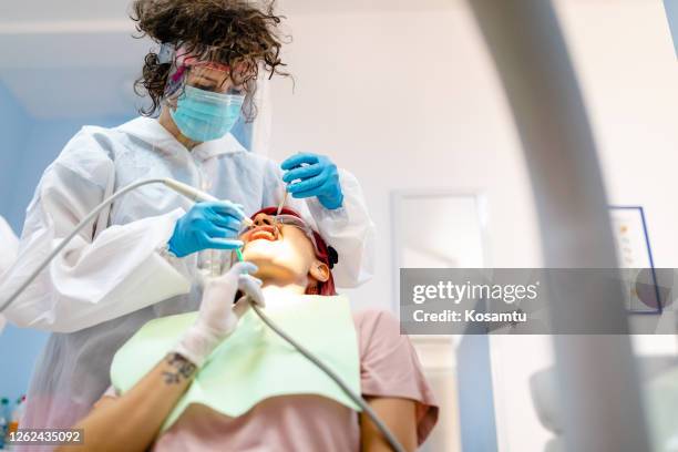 vrouwelijke parodontist verwijdert harde en zachte afzettingen uit het glazuur, zodat de patiënt een mooie glimlach kan hebben - parodontitis stockfoto's en -beelden