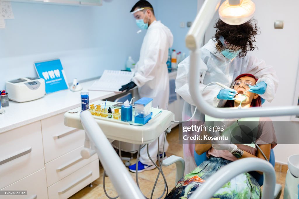 Female Endodontist Treating Caries While Using Angled Mirror And Dental