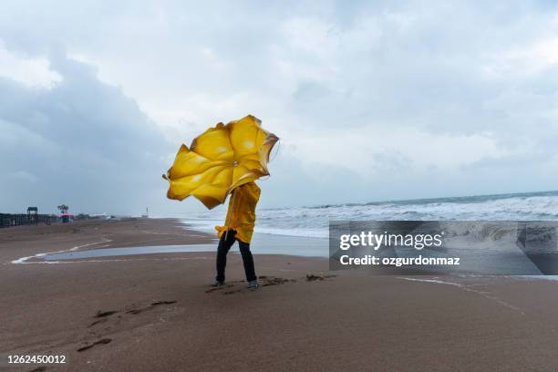 hombre en la playa tormentosa - viento fotografías e imágenes de stock