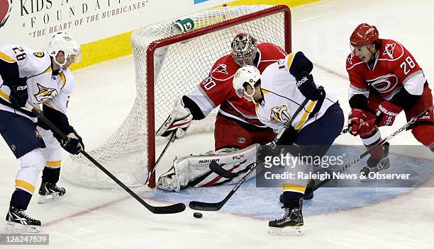 The Nashville Predators' Chris Mueller gets ready to put the puck past Carolina Hurricanes goalie Justin Peters and defenseman Justin Faulk for the...
