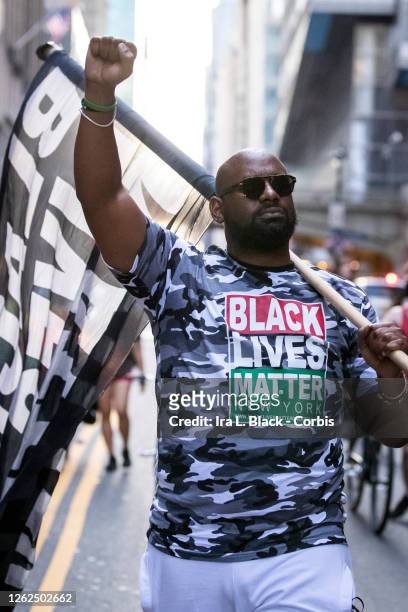 July 26: Hawk Newsome, Chairperson of Black Lives Matter Greater New York walks down the street with a Black Lives Matter flag over his shoulder and...