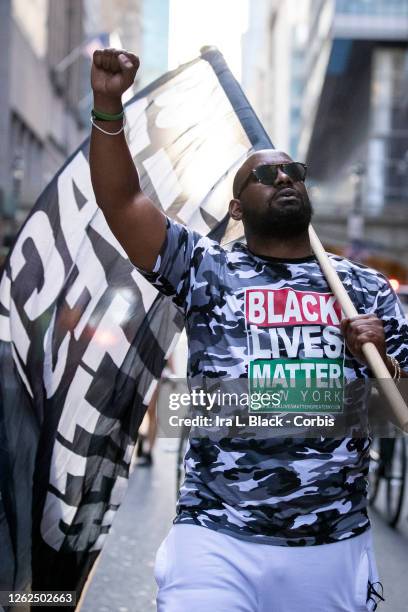July 26: Hawk Newsome, Chairperson of Black Lives Matter Greater New York walks down the street with a Black Lives Matter flag over his shoulder and...