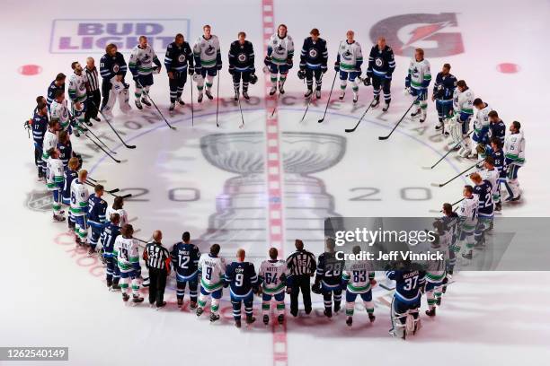 Members of the Vancouver Canucks and the Winnipeg Jets stand at center ice during the national anthem before an exhibition game prior to the 2020 NHL...