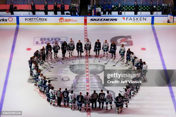 Members of the Vancouver Canucks and the Winnipeg Jets stand at center ice during the national anthem before an exhibition game prior to the 2020 NHL...