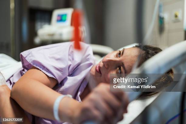 jonge zwangere vrouw die klaar voor natuurlijke bevalling maakt terwijl het liggen in haar het ziekenhuisbed - giving birth stockfoto's en -beelden