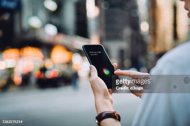 over the shoulder view of young asian businesswoman using ai assistant on smartphone on the go in financial district in the city - business people chatting stock-fotos und bilder
