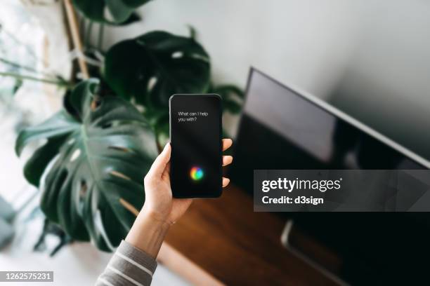 close up of woman's hand using ai assistant on smartphone in the living room at home - speech recognition stock pictures, royalty-free photos & images