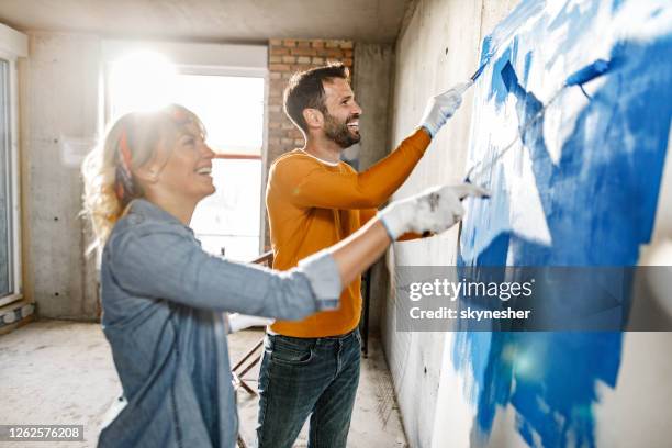 young happy couple painting during home renovation process. - couple painting stock pictures, royalty-free photos & images