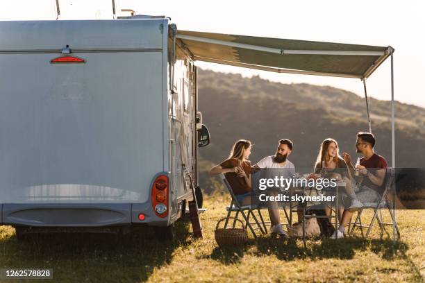 amigos felices que se comunican en la mesa de picnic junto al remolque del campamento en el día de verano. - trailer fotografías e imágenes de stock