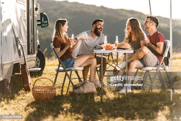 junge fröhliche paare sprechen am picknicktisch am lageranhänger. - garden table stock-fotos und bilder