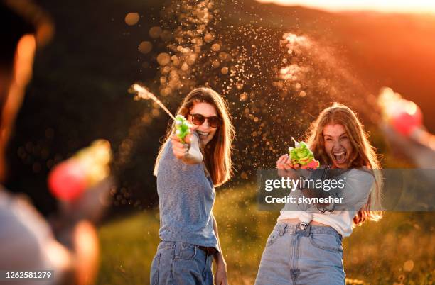 ¡pelea de armas de agua al atardecer! - pistola de agua fotografías e imágenes de stock