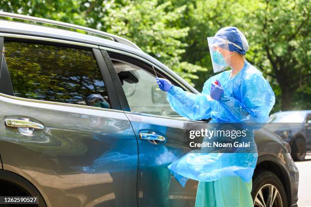 Health worker wears a protective face mask, face shield and gloves while performing a COVID-19 nasal swab test on a friend of the photographer on the...