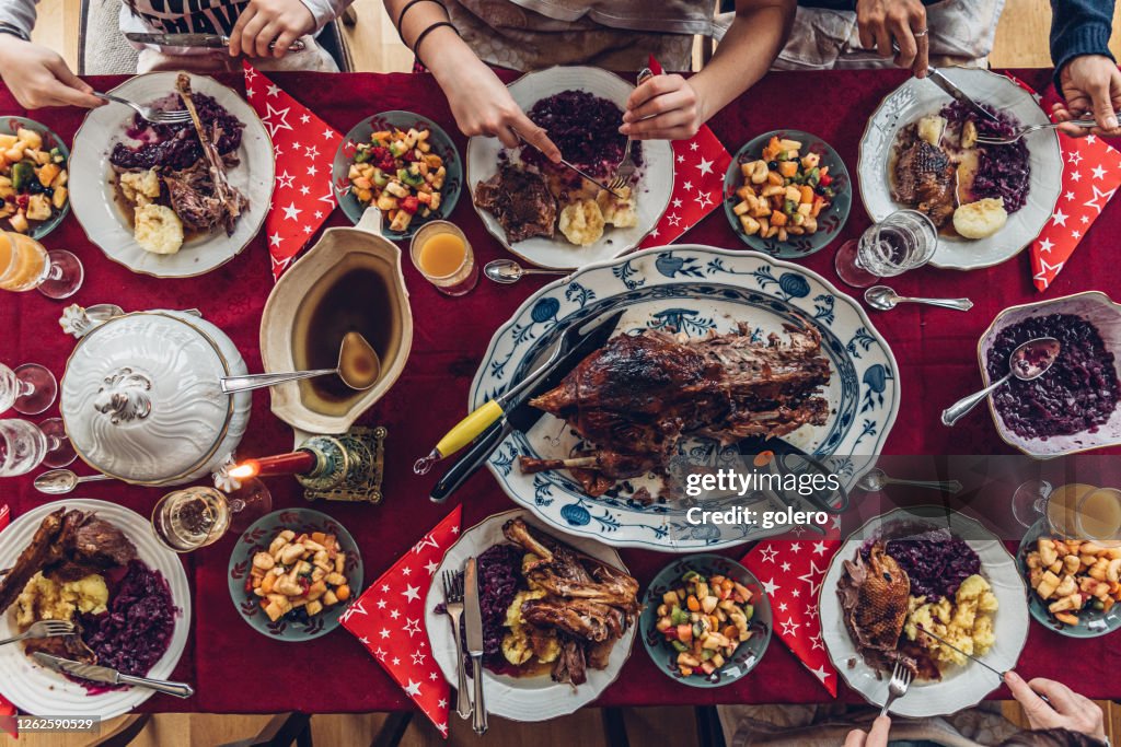 Family eating traditional german celebrity goose roast at festive Christmas table