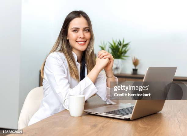 jonge en gelukkige vrouwelijke arts die videovraag met laptop thuis heeft. - coffee chat stockfoto's en -beelden