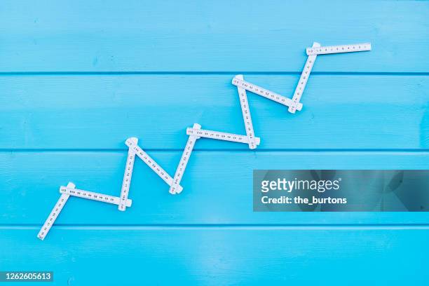 folding ruler in shape of a stock curve on blue painted wooden background - measuring success stock pictures, royalty-free photos & images