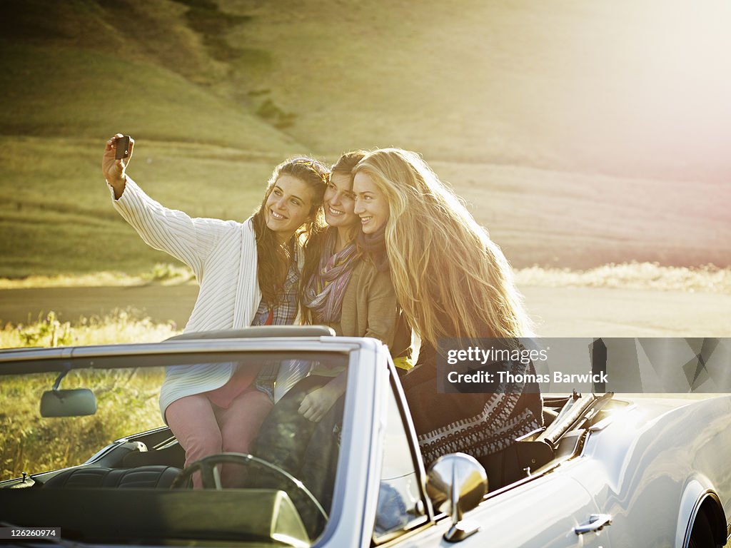 Women sitting in backseat taking digital photo