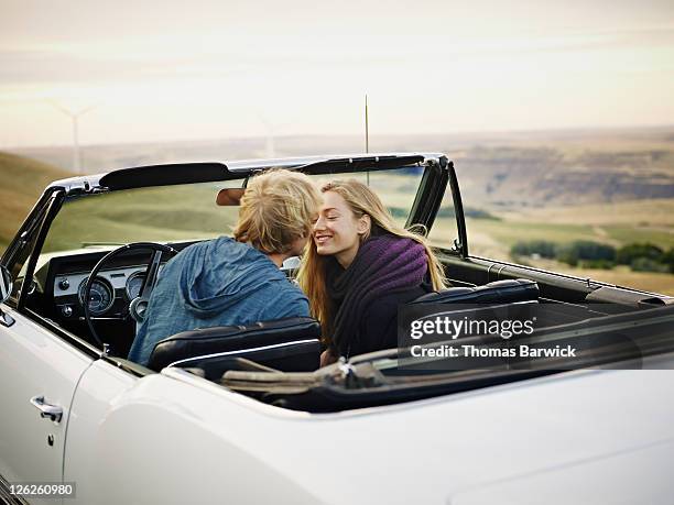 couple leaning in to kiss in convertible - auto küssen stock-fotos und bilder