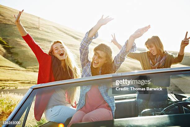 women in parked convertible with arms in air - young women only stock-fotos und bilder