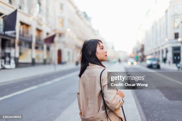 side view of a young woman exploring and discovering regent street, london - oxford street london stock-fotos und bilder