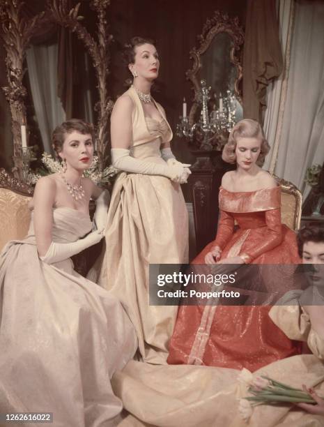 Three female models, including from left, Pamela Crampton, Barbara Goalen and Sally Ann Vivian wear two evening gowns in silk by John Cavanagh and a...