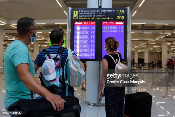 Passengers look at the flight board at Palma de Mallorca airport on July 30, 2020 in Mallorca, Spain. The United Kingdom, whose citizens comprise the...