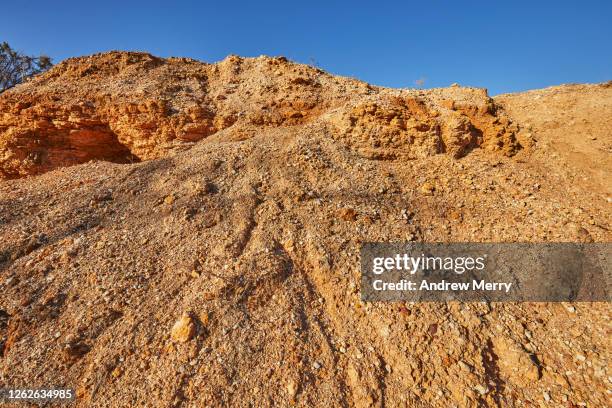 eroded desert landscape, weathered earth and blue sky - mining low angle foto e immagini stock