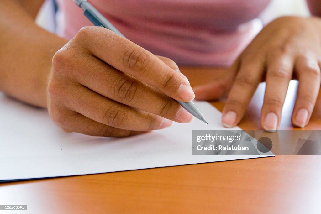 Close-up of adult hands writing with pen and paper