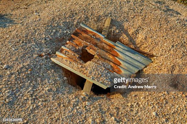 mineshaft hole in the ground with flimsy corrugated iron cover - opal mining stock pictures, royalty-free photos & images