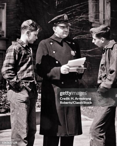 1940s 1950s Two Teenage Boys On The Street Confronted By Police Officer Reading Truancy Letter Summons Rules Warrant