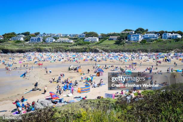 Tourists enjoy the beach on July 30, 2020 in Polzeath, United Kingdom. Tourists are slowly returning to Cornwall after lockdown measures introduced...