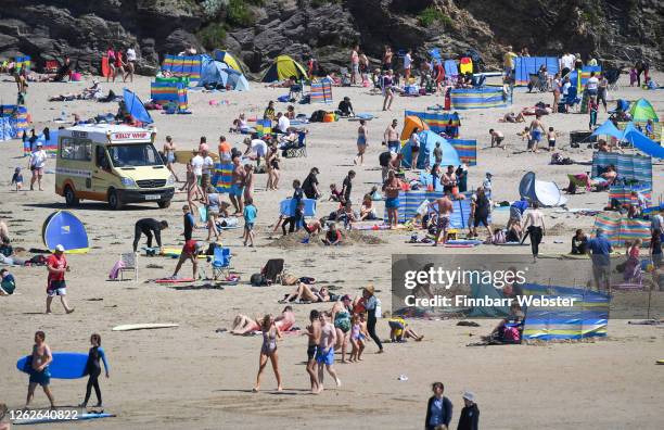 Tourists enjoy the beach on July 30, 2020 in Polzeath, United Kingdom. Tourists are slowly returning to Cornwall after lockdown measures introduced...