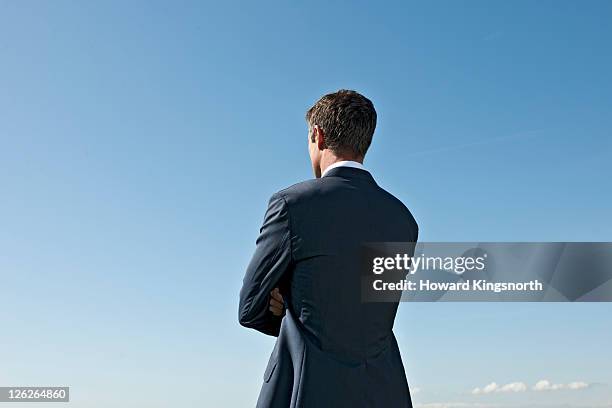 man with arms folded looking into distance - man back foto e immagini stock
