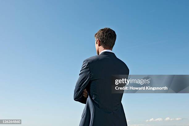 man with arms folded looking into distance - rear view of man stock pictures, royalty-free photos & images
