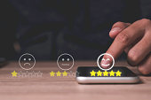 Hand touch on mobile phone to add five yellow stars to customer evaluates products and services. Customer satisfaction and marketing survey rating concept.