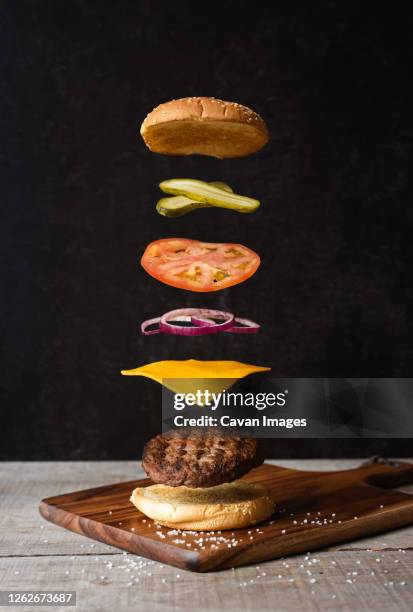 separated burger with floating ingredients on black background. - burger mid air stock pictures, royalty-free photos & images