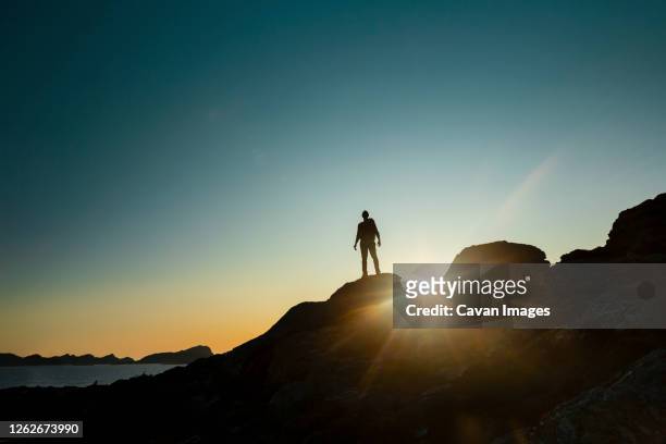 man silhouette over a rock at sunset - challenge ストックフォトと画像