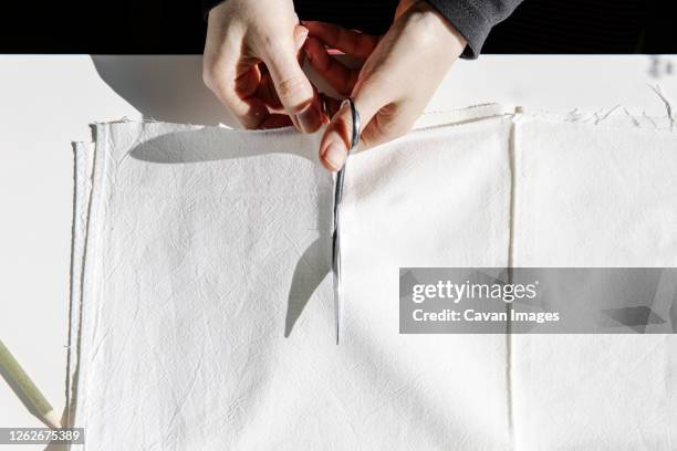 crop sewer cutting piece of fabric on a table for making masks - wearing cloth face mask stock pictures, royalty-free photos & images