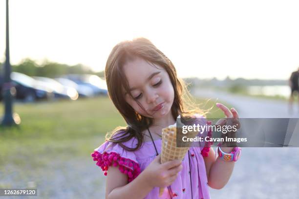 a little girl in a pink dress holding a big waffle cone - mr whippy ice cream stock pictures, royalty-free photos & images