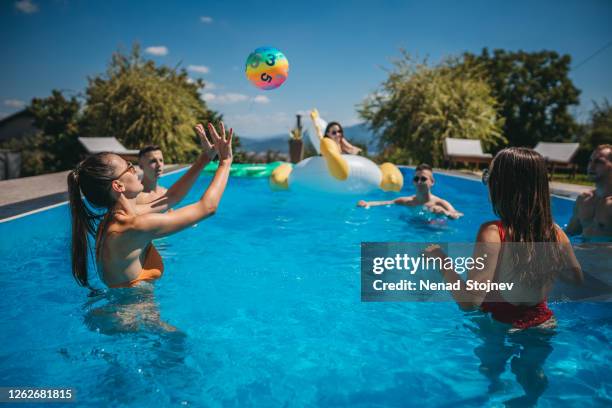 freunde spielen volleyball im schwimmbad - kids pool games stock-fotos und bilder