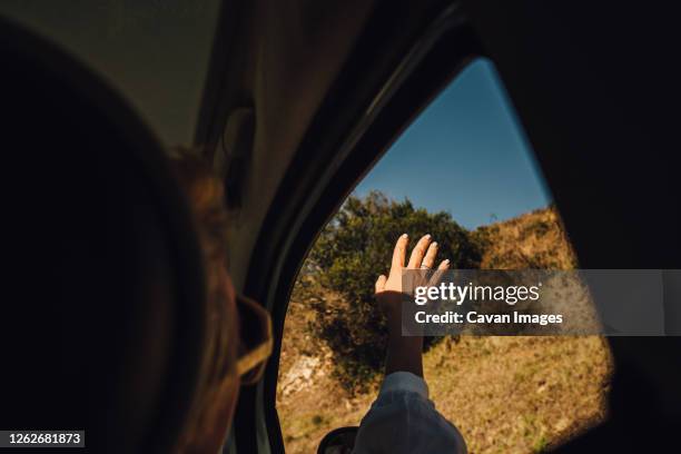 female hand catching air in side window while driving a car - zwaaien gebaren stockfoto's en -beelden