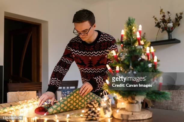 young man packs christmas presents for friends and family - same action stock-fotos und bilder