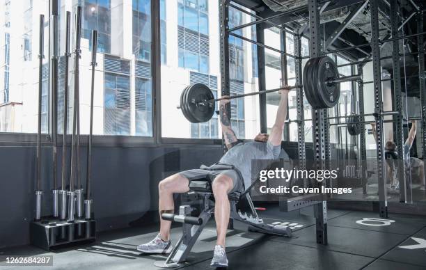 man working out with barbells in urban gym in bangkok - bench press stock pictures, royalty-free photos & images